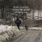 Photo of a man and a dog running on a trail in the woods with snow on the ground surrounding them. Bolded at the top of the picture are the words Noah Kahan- Stick Season, and written smaller underneath it says We’ll All Be Here Forever.